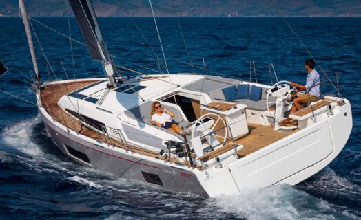Eine Oceanis 46.1 segelt mit Crew im Cockpit vor bergiger Küste – Yachtcharter Kroatien